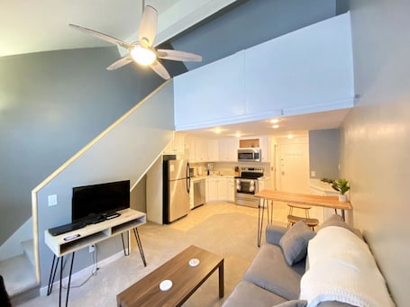 A compact living space with a kitchenette, a dining area, and a seating area with a sofa and coffee table.