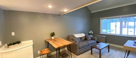 Een woonkamer met een grijze bank, een houten salontafel en een witte radiator.