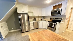 A kitchen with white cabinets, stainless steel appliances, and a wooden countertop. - Cozy Condo in the Heart of Smugglers' Notch Resort (Cambridge)