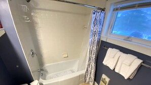 A bathroom with a bathtub, toilet, and a window with a view. - Cozy Condo in the Heart of Smugglers' Notch Resort (Cambridge)