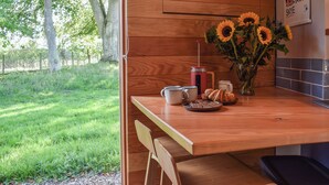 En træbordplade med en kaffemaskine, en vase med solsikker og et fad med croissanter.