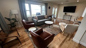 A modern living room with a sofa, armchairs, a coffee table, and a TV. - Upper Chesapeake Getaway - Newly Renovated (Perryville)