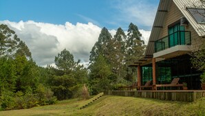 Una casa moderna con un amplio ventanal, un estanque y una terraza de madera.