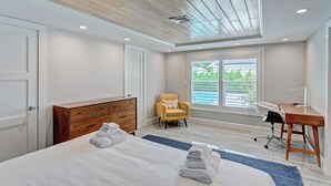 Une chambre à coucher moderne avec un grand lit, une commode en bois, un bureau et une chaise.