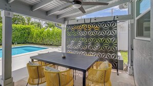 Une terrasse extérieure avec une piscine, une table et des chaises en osier jaune.
