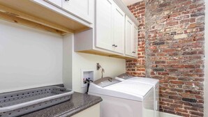 Een wasserette met een bakstenen muur, een wasmachine en een droogrek.