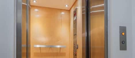 Un ascensor con interior metálico, un panel de control y piso de madera.
