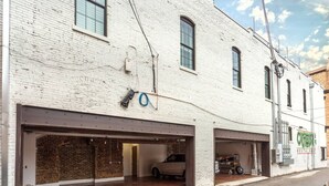 Een wit bakstenen gebouw met twee garage-deuren, een zichtbaar voertuig en een bord met een restaurant.