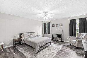 Une chambre à coucher comprenant un lit, un bureau, une chaise et un ventilateur de plafond.