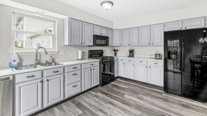 A modern kitchen with grey cabinets, stainless steel appliances, and a wooden floor. - 3-min from downtown Fishers (Fishers)