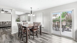 A dining area with a wooden table and chairs, a ceiling fan, and a view through a sliding glass door to an outdoor patio. - 3-min from downtown Fishers (Fishers)