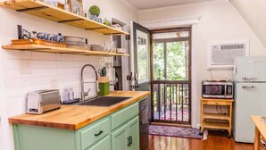 A compact kitchen with a wooden countertop, a built-in sink, and a green cabinet. There is a microwave and a small table with a chair. - The Boho Loft: colorful, cozy, comfortable 1BR (Hot Springs)