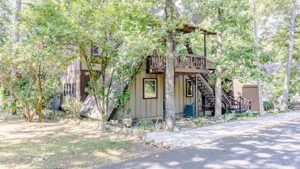 A rustic cabin with a wooden staircase leading to a door, surrounded by trees. - The Boho Loft: colorful, cozy, comfortable 1BR (Hot Springs)