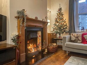 A cozy living room with a fireplace, a Christmas tree, and a sofa with a deer pillow. - 3 bedroom accommodation in Pickering (Pickering)