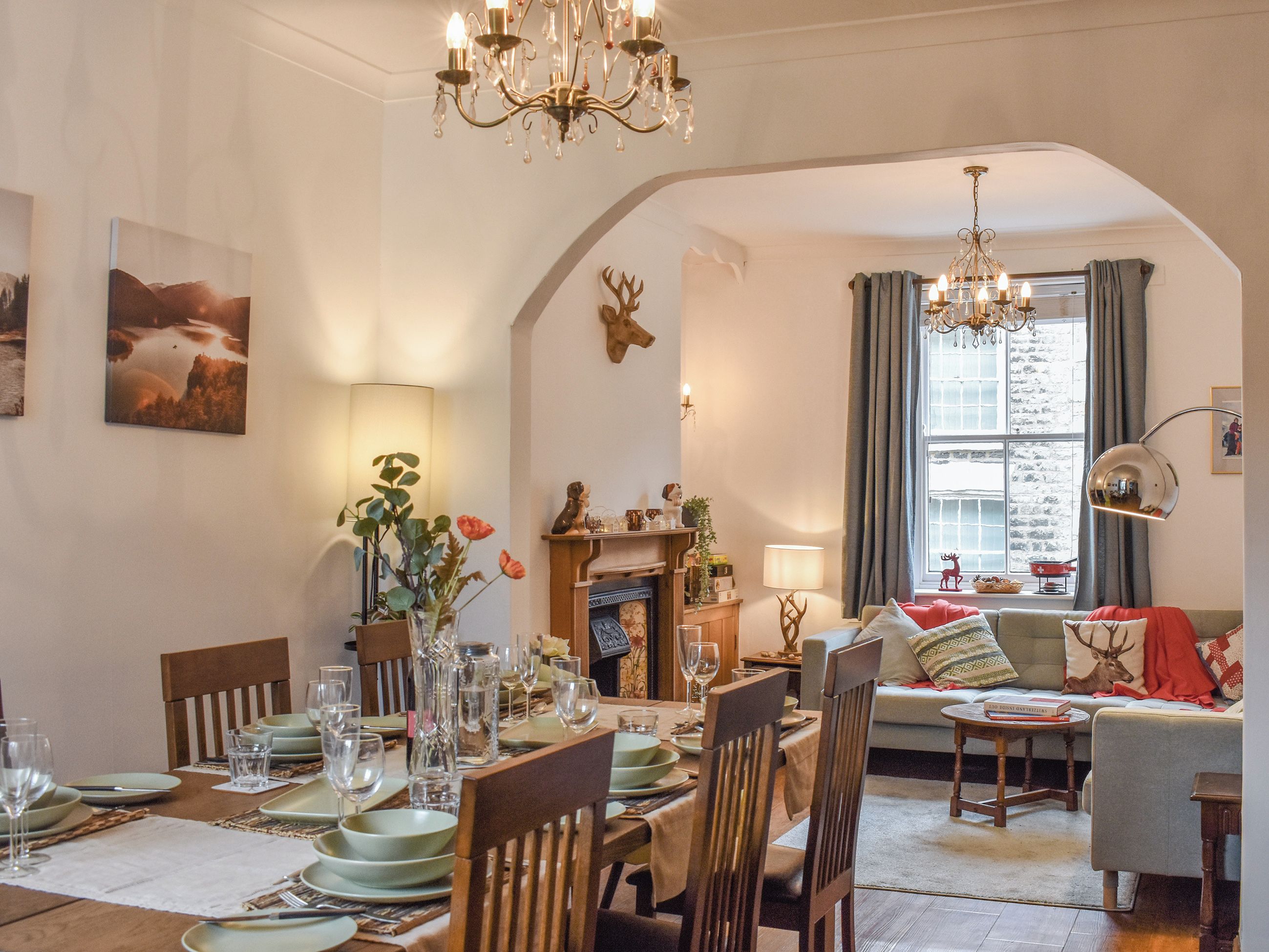 A dining area with a table set for six, a fireplace, and a cozy seating area with a sofa and a side table.
