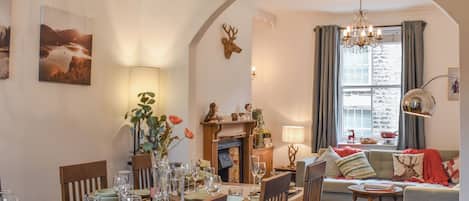 A dining area with a table set for six, a fireplace, and a cozy seating area with a sofa and a side table.
