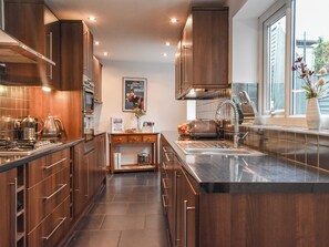 Una cocina moderna con armarios de madera oscura, electrodomésticos de acero inoxidable y una isla central con un lavamanos.