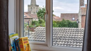 Une fenêtre donnant sur le clocher d’une église et sur des immeubles d’habitation.