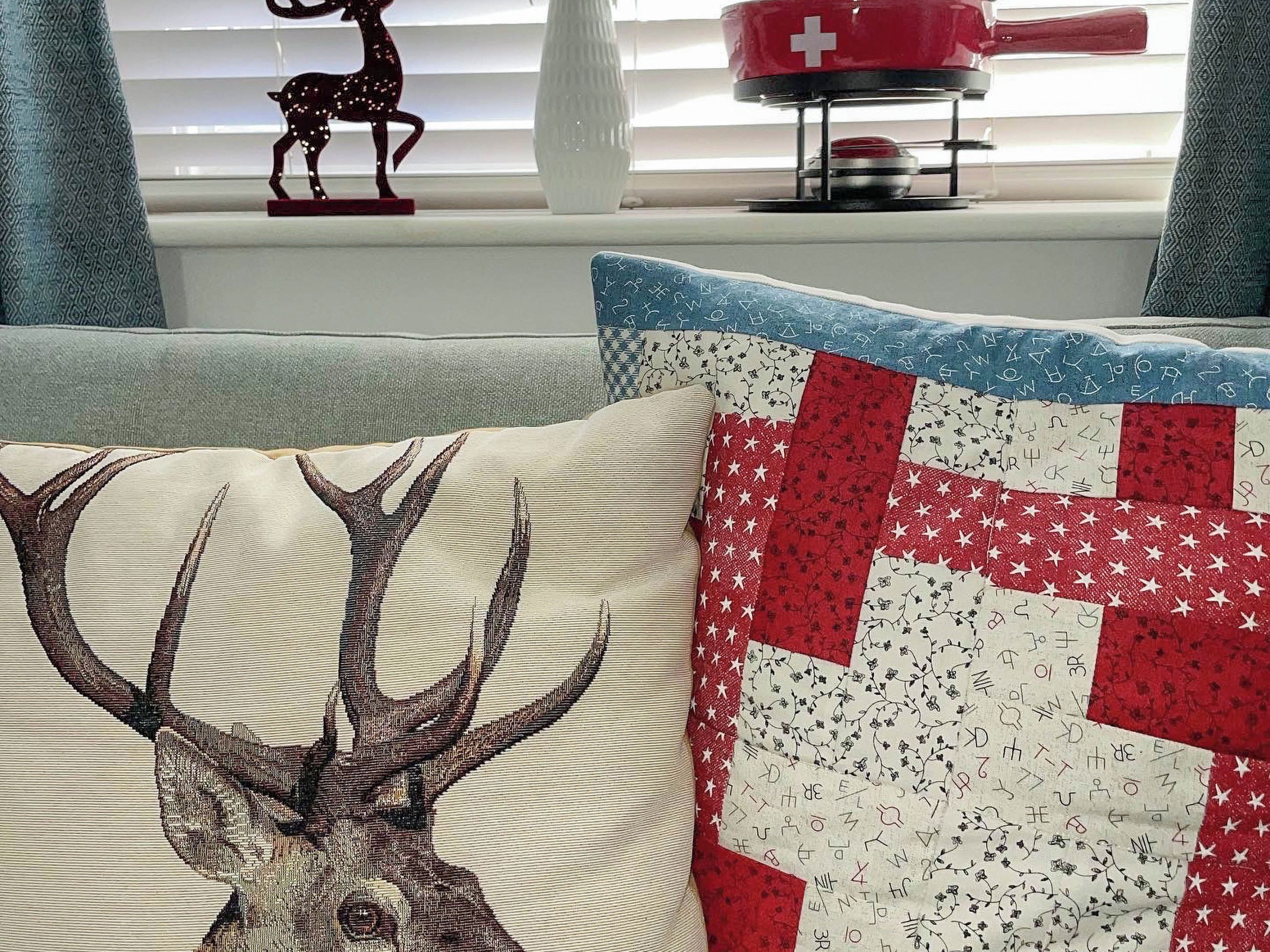 A living room with a couch, a decorative deer pillow, and a quilt with a star pattern.