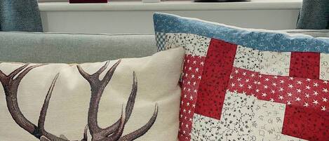 Uma sala de estar com um sofá, um travesseiro decorativo de veado e um edredom com padrão de estrelas.