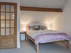 A bedroom with a wooden bed frame, a large window, and a door with glass panels.