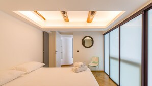A modern hotel room with a skylight, a large bed, a chair, and a view of the outside. - Design Duplex at National Museum (Napoli)