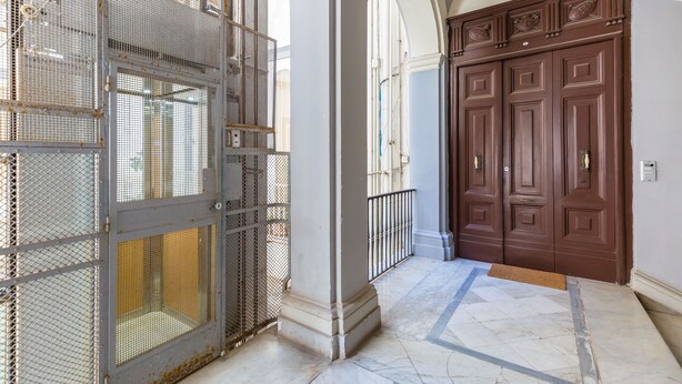 A hallway with a metal gate, a wooden door, and a marble floor. - Design Duplex at National Museum (Napoli)