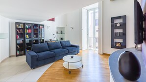 A modern living room with a blue sofa, a white coffee table, and a bookshelf filled with books. - Design Duplex at National Museum (Napoli)