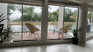A spacious room with large windows offering a view of a pool and palm trees. - Confortable y amplio estudio D9 (Cozumel)
