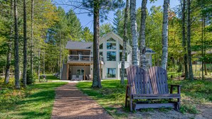 A cabin with a deck, surrounded by trees.