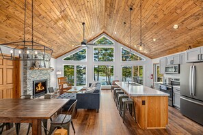 A spacious kitchen with a large island, a fireplace, and a view of the outdoors. - Up North- Brand New- Lake Front House- 4 bedrooms, 3 baths (Eagle River)