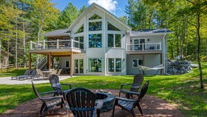 A large, multi-level house with a deck and outdoor seating area.