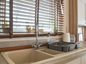 Una cocina con un lavamanos doble, persianas de madera y una ventana que da a zonas verdes.