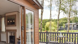 A wooden deck with two wicker chairs and a table, overlooking a forested area. - 2 bedroom accommodation in Landford, near New Forest (Landford, near New Forest)