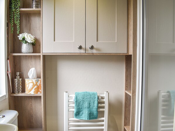 A bathroom with a wooden vanity, a towel rack with a teal towel, and a toilet.