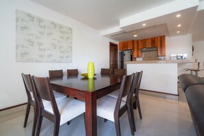 A modern dining area with a wooden table and chairs, a yellow vase, and a kitchen in the background. - Wayak 301 - Center of Playa del Carmen (Playa del Carmen)