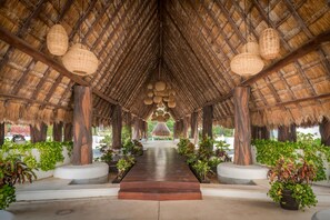 A covered walkway with a thatched roof, wooden pillars, and hanging woven light fixtures. - Wayak 301 - Center of Playa del Carmen (Playa del Carmen)