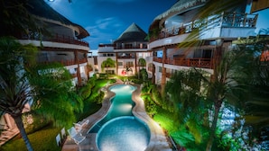 Un resort con diversi edifici, una piscina centrale e una rigogliosa vegetazione.