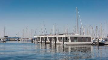 Un puerto deportivo con varias embarcaciones amarradas, que incluye una serie de estructuras flotantes blancas con ventanas y barandillas.