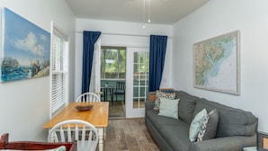 A cozy living room with a grey sofa, a wooden dining table, and a map on the wall.