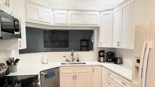 A modern kitchen with white cabinetry, a black stove, and a stainless steel sink.