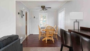 Un coin repas comprenant une table et des chaises, un ventilateur de plafond et une fenêtre avec des stores.