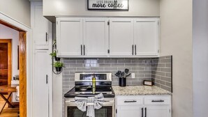 Una cocina moderna con armarios blancos, una estufa de acero inoxidable y un salpicadero de azulejos.