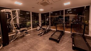 Un gimnasio en casa con equipo de ejercicio diverso, incluyendo una cinta de correr, bicicleta estática y máquina de pesas.