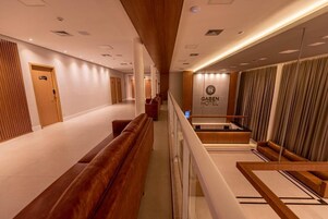Pasillo de hotel con bancos de madera, un mostrador de recepción y un letrero del Hotel Gabin.