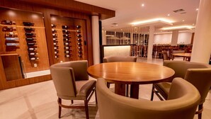 Un comedor moderno con una mesa redonda de madera rodeada de sillas de cuero, una estantería para vinos con botellas y un interior bien iluminado.