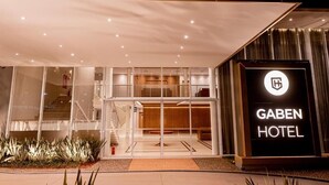 Una entrada de hotel moderna con fachada de vidrio, una escalera visible y un cartel llamativo del Hotel Gaben.