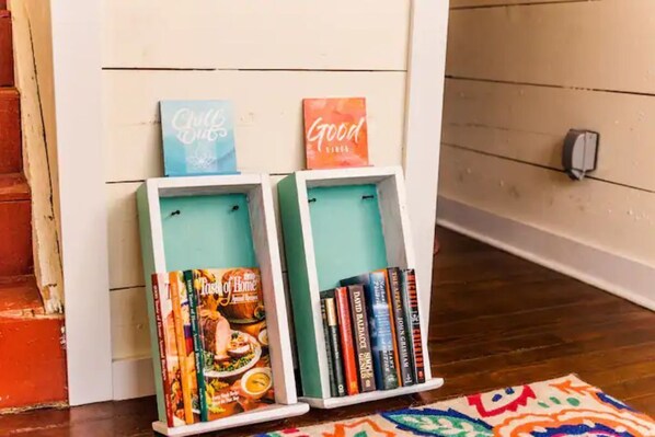 Two white bookshelves against a wall with two framed signs above them. - Charming 1BR Suite at Historic Ruby Red, downtown (Hot Springs)