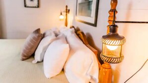 A bed with white pillows and a wall-mounted lamp.