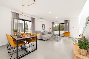 Uma sala de estar moderna com sofá, mesa de jantar, cadeiras e mesinha de centro.